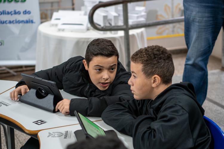 Crianças conversando enquanto manuseiam o tablet